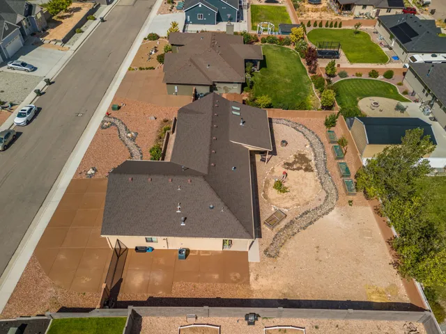 Expansive property featuring a brown shingle roof, tan stucco exterior, and a large concrete patio