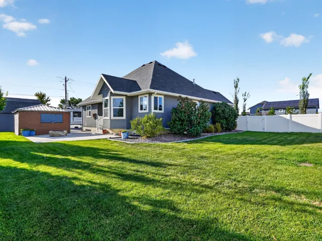 Expansive backyard with a manicured lawn, dedicated patio area, and a private storage shed