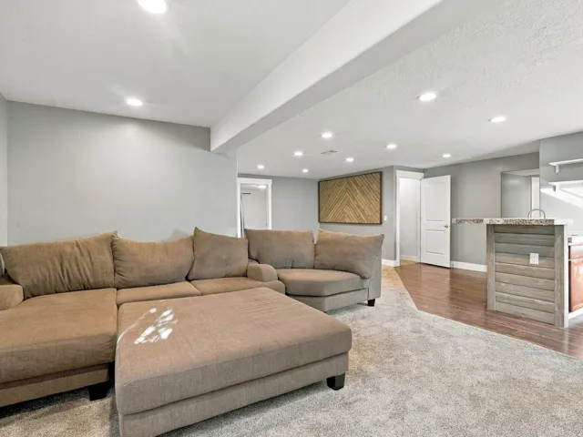 Recessed lighting, wood-finish flooring, light gray wall tones, and a built-in bar with a stone countertop