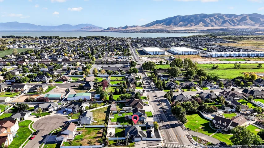 Residential neighborhood with mature trees, surrounded by a mountain range and a large body of water