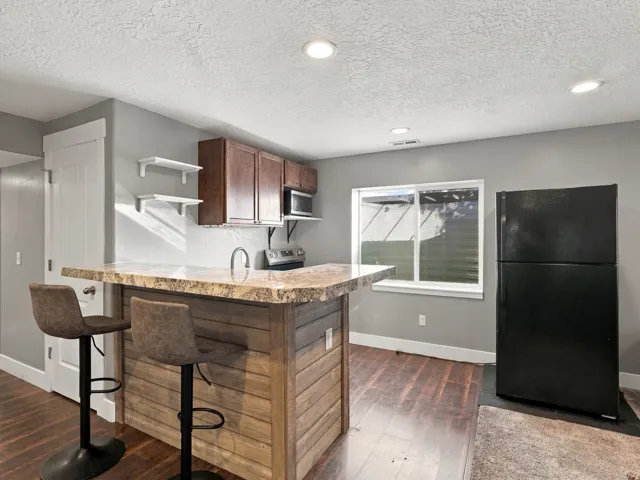 Kitchenette featuring wood-finish flooring, a stone-finish countertop, and dark wood cabinetry