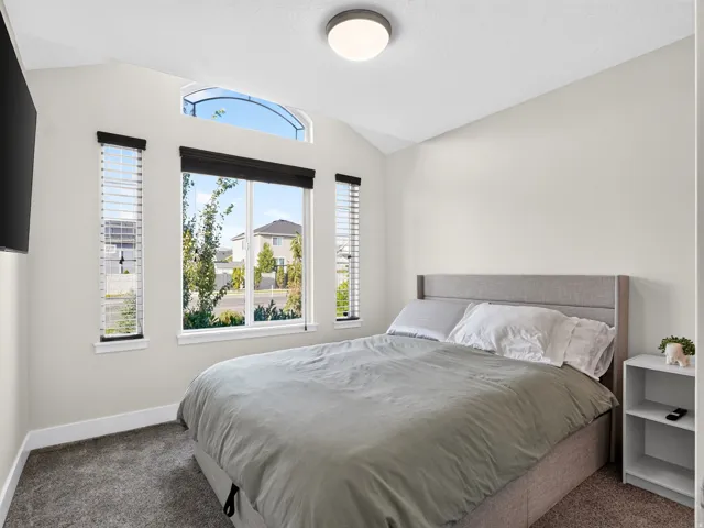 Vaulted ceiling with an arched transom window, large picture window with two vertical accent windows, and plush carpet flooring