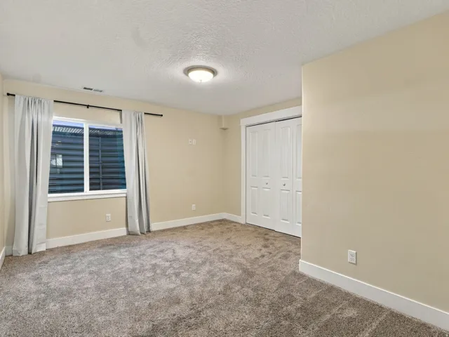 Neutral-toned walls, gray carpet flooring, white trim, and a window with horizontal blinds