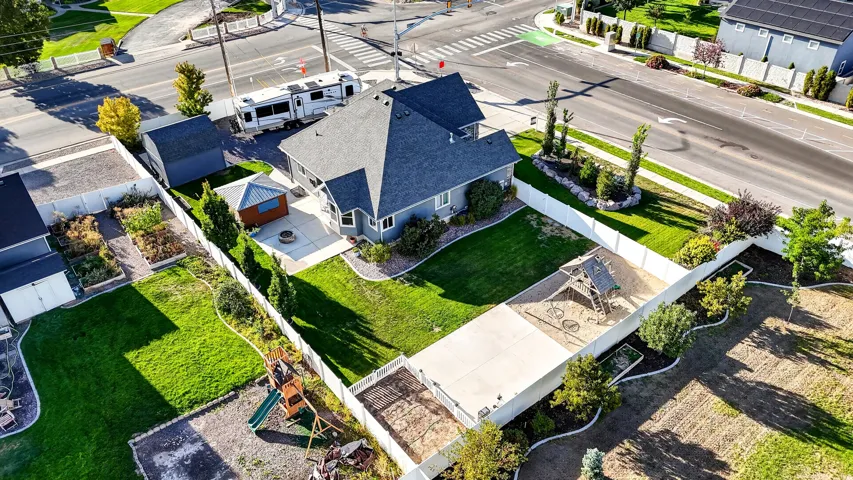 Expansive fenced backyard featuring a manicured lawn, concrete patio, and a dedicated garden area