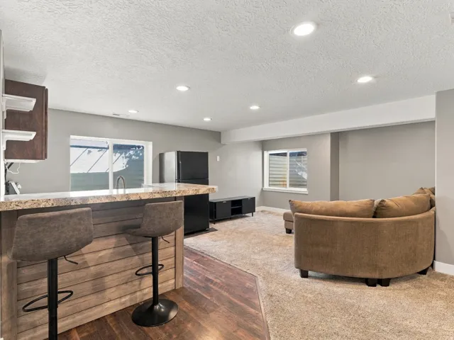 Integrated living space featuring a built-in bar with a stone-finish countertop and wood-paneled base