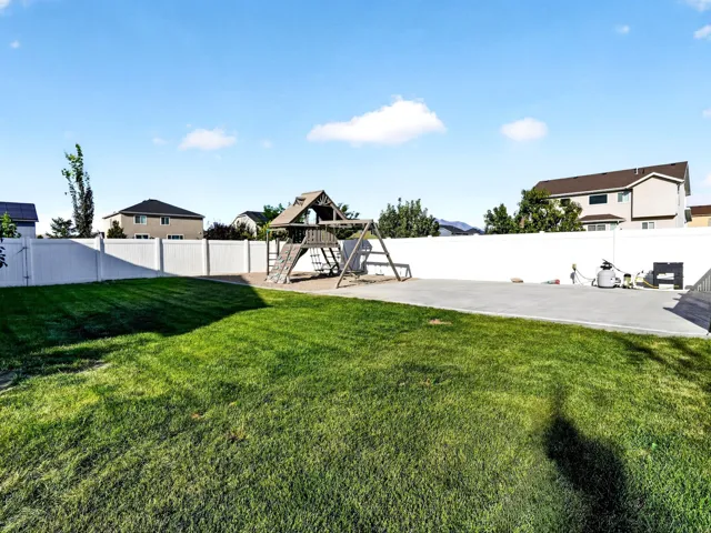 Expansive lawn area with a white privacy fence and a concrete patio