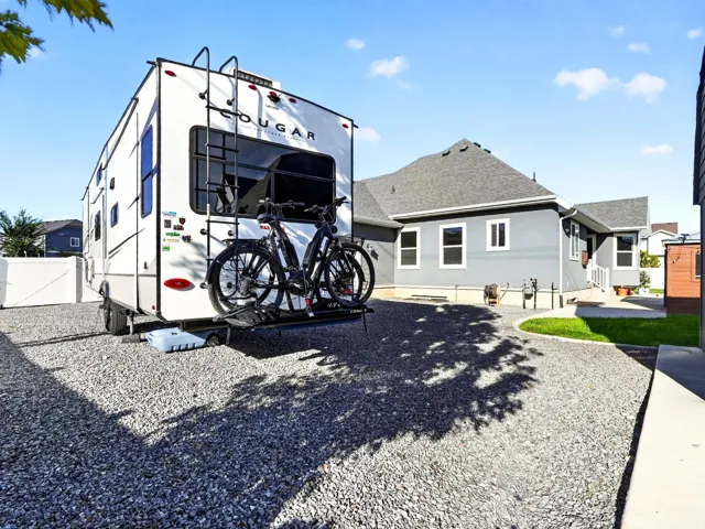 Gravel parking area with a separate side yard, white fencing, and a stucco exterior