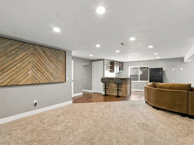 Recessed lighting, wood-finish flooring, built-in wet bar, and a patterned wood-finish accent wall