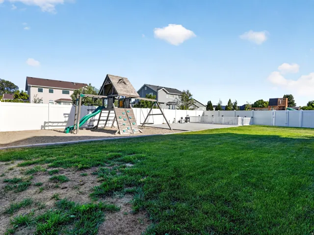 Spacious outdoor area featuring a wooden play structure with a slide and swings
