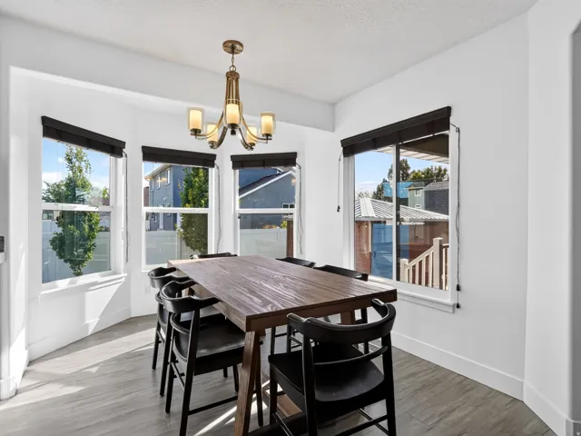 Bay window with multiple large windows, wood-finish flooring, and a contemporary chandelier