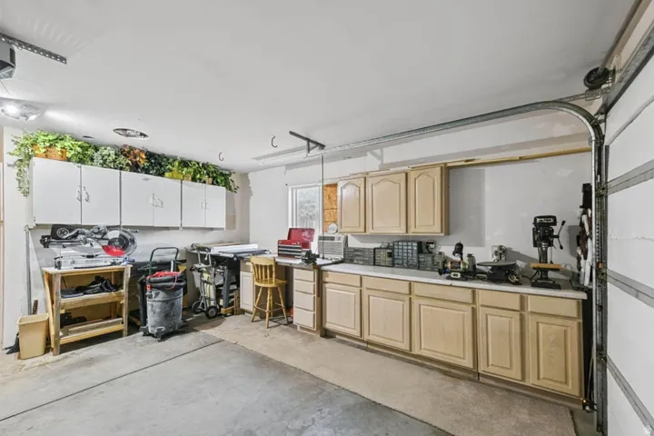 Garage workspace featuring extensive cabinetry, built-in countertops, and concrete flooring