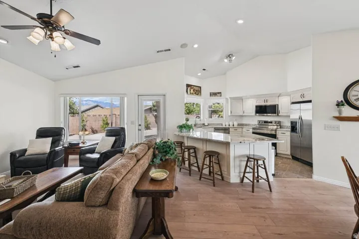 Spacious living area with vaulted ceilings, wood-finish flooring, and a ceiling fan