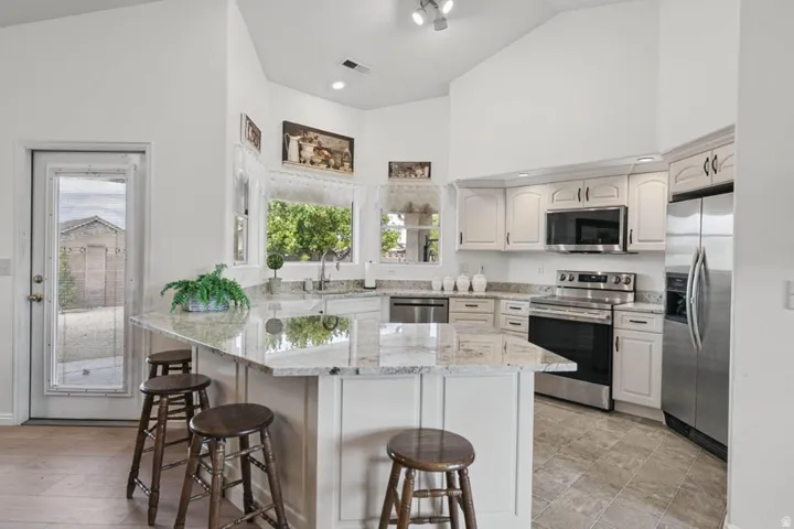 Kitchen featuring light cabinetry, stainless steel appliances, granite countertops, and tile flooring