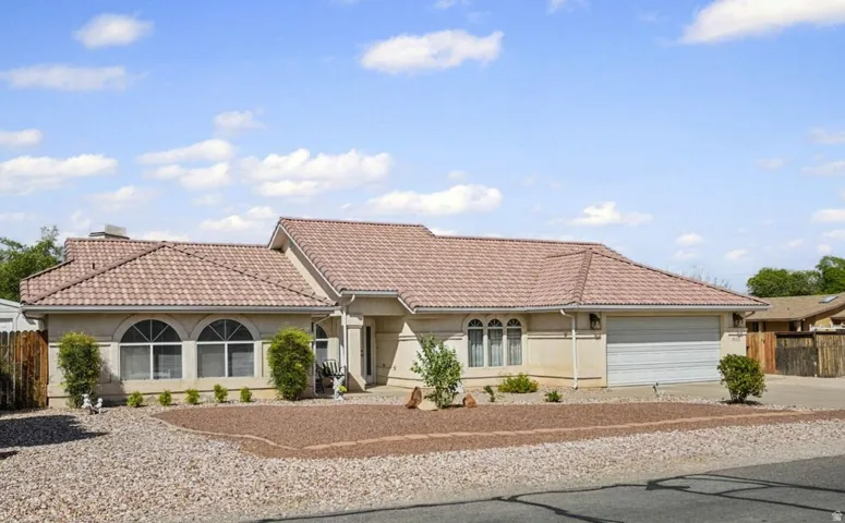 Elegant single-story residence featuring a clay tile roof, arched architectural details, and a two-car garage