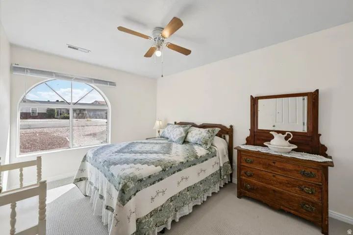 Arched window with upper transom, ceiling fan with integrated lighting, and neutral wall tones