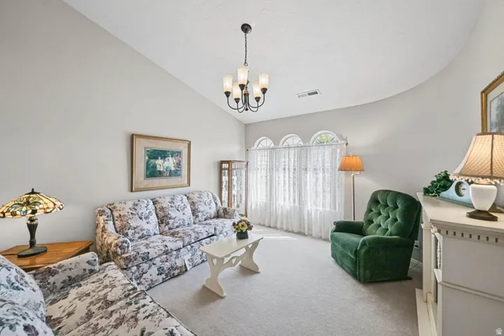 Vaulted ceiling, arched windows, chandelier, light-colored walls, and carpeting
