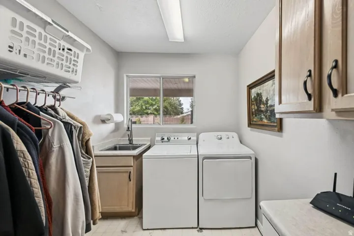 Utility room featuring a built-in sink with cabinetry, overhead storage cabinets, and a clothes hanging rod