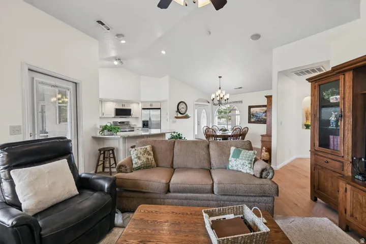 Vaulted ceilings, recessed lighting, wood-finish flooring, white cabinetry, and a ceiling fan
