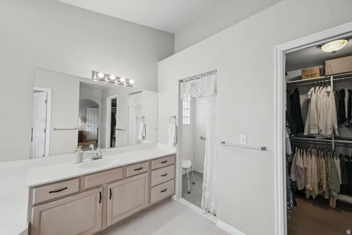 Extended vanity with dual sinks, overhead lighting fixture, and full-width mirror