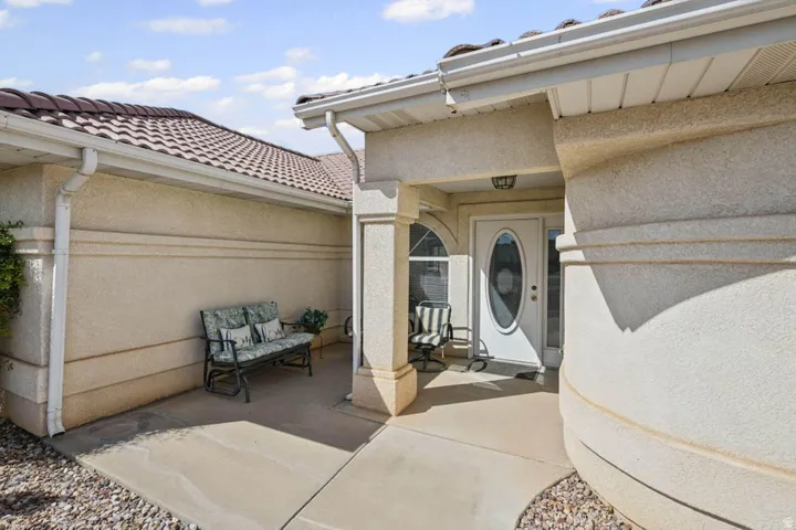 Stucco exterior with decorative banding, white oval-lite entry door, tile roof, and covered entryway