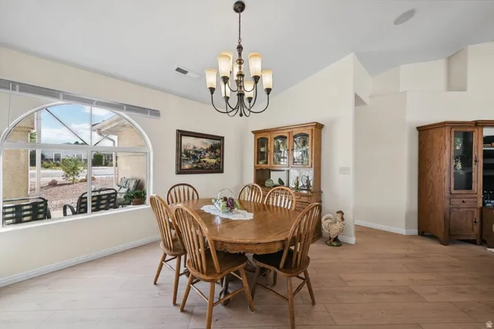 Arched window with transom, neutral wall tones, wood-finish flooring, vaulted ceiling, and a multi-light chandelier