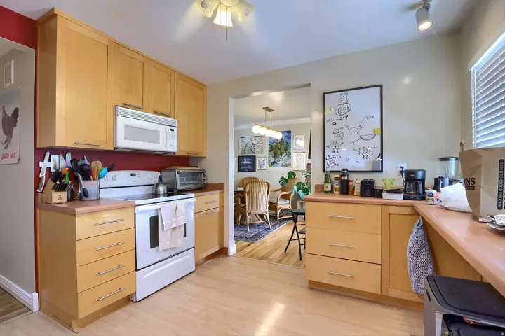Kitchen featuring light wood-finish cabinetry, light wood-finish flooring, a built-in microwave, and track lighting