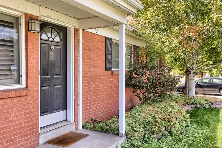 Brick exterior with a covered entryway and a paneled front door featuring an arched transom window