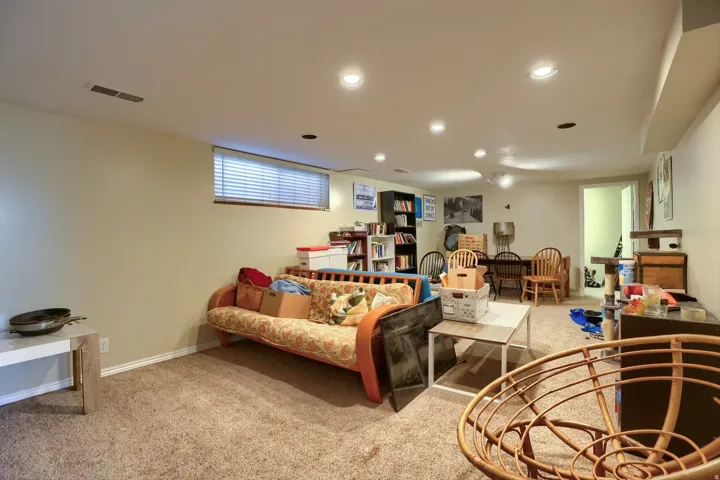 Recessed lighting, carpet flooring, a built-in bookshelf, and a window with blinds