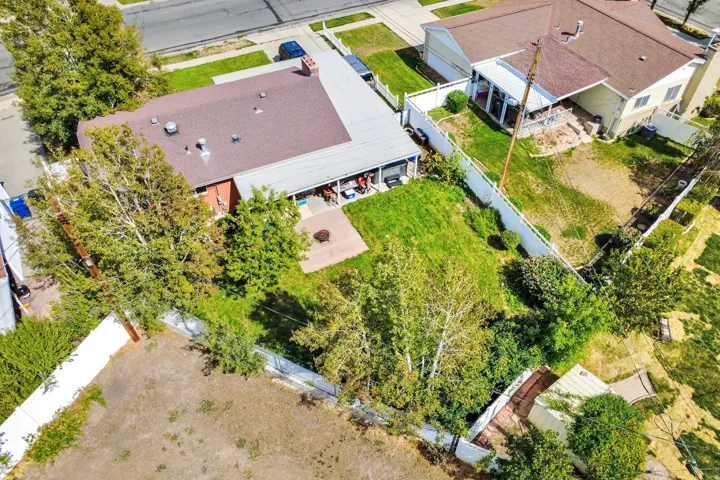 Expansive backyard with a manicured lawn, established trees, and a concrete patio