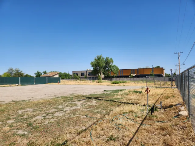 Expansive open lot with a chain-link fence perimeter and visible utility hookups