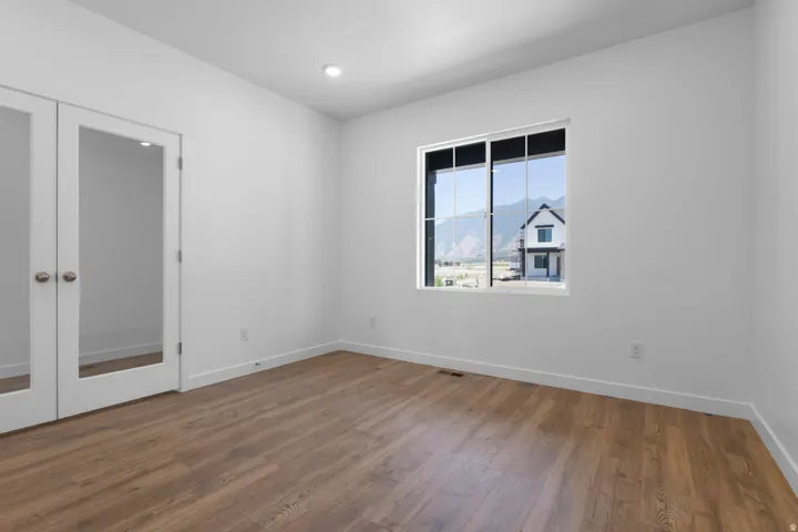 Recessed ceiling lighting, wood-finish flooring, white walls, and double French doors with glass panels