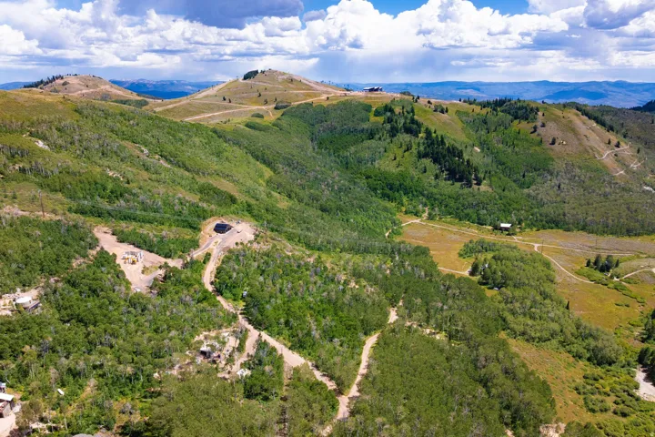 Expansive mountain landscape with diverse foliage, natural terrain, and distant peaks