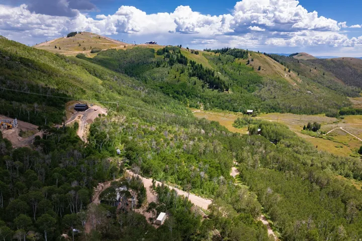 Expansive mountainous terrain featuring lush green foliage and scattered structures