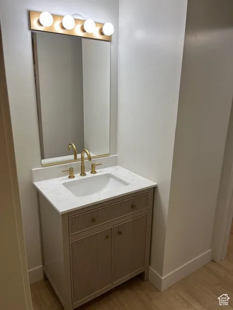 Vanity with reeded paneling, gold-tone hardware, integrated sink, and stone-finish countertop