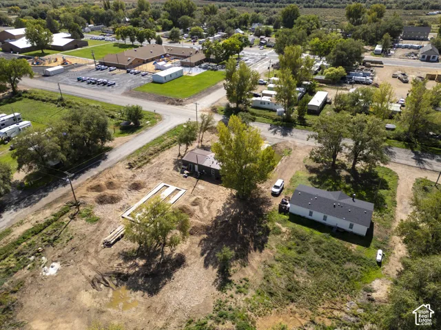 Expansive lot featuring a single-story structure with a dark shingle roof and light-colored siding, surrounded by mature trees and open land