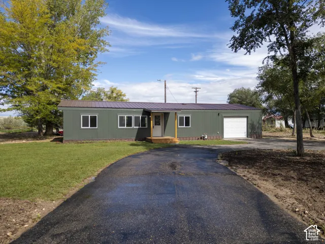 Green siding exterior with a brown metal roof, featuring a white garage door