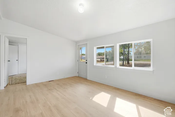 Light wood-finish flooring, white walls, and multiple windows with white frames