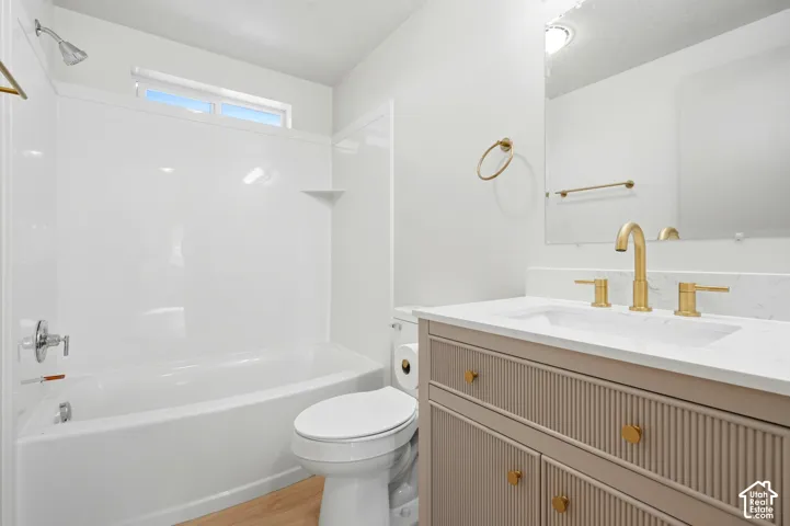 White vanity with a rectangular integrated sink, gold-finish faucet, and a large mirror