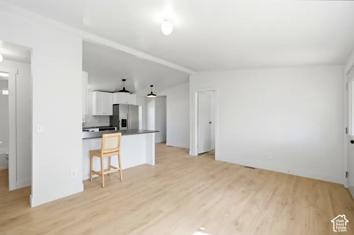 Open-concept living space with wood-finish flooring, white walls, and recessed lighting