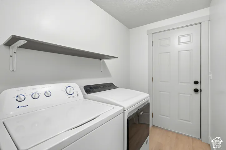 Upper shelving unit, light wood-finish flooring, paneled door, and built-in washing machine