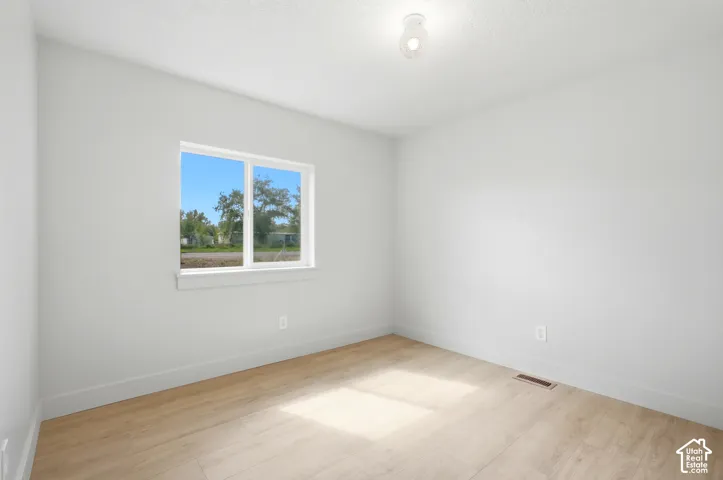 Neutral wall finishes with a single window, wood-finish flooring, and a ceiling-mounted light fixture