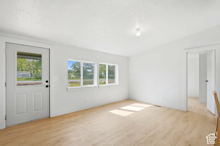 White interior walls, wood-finish flooring, multiple windows, recessed ceiling light, and an interior doorway