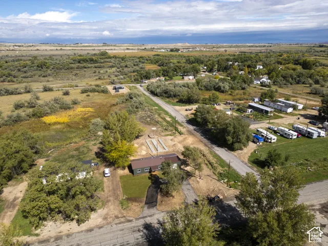 Expansive rural setting with varied vegetation, a single-story residence with a dark roof, and surrounding unpaved access roads