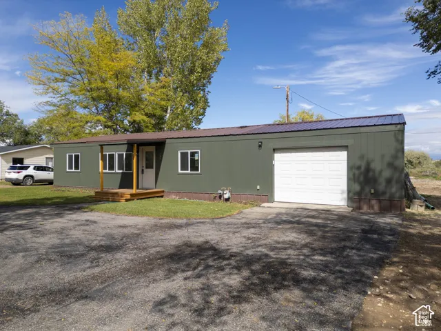 Green siding exterior with a metal roof, attached garage, and a wooden front porch