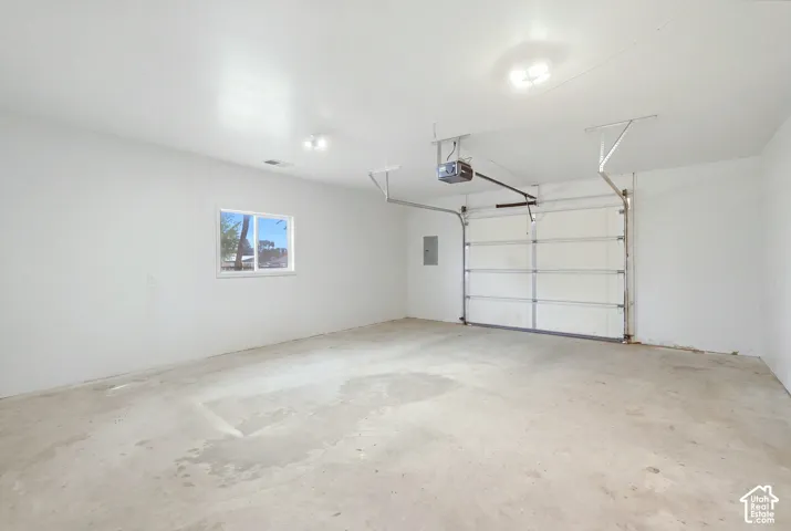 Spacious garage featuring a concrete floor, overhead lighting, and a single window