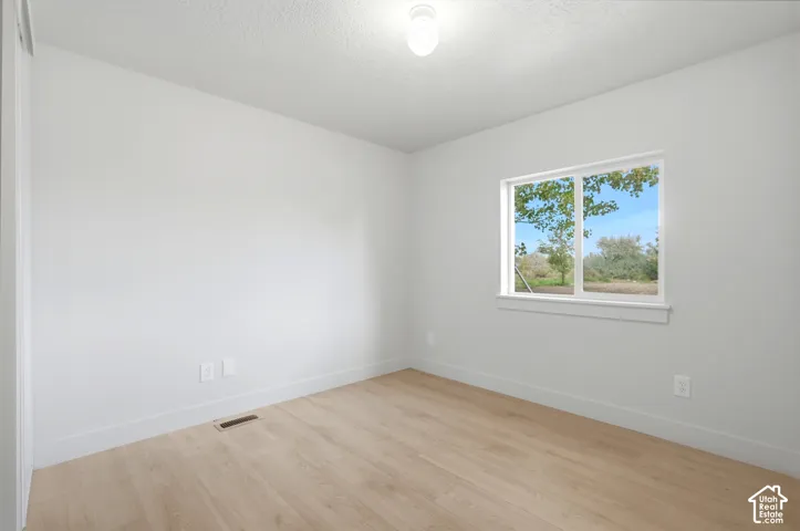 Light wood-finish flooring, white walls, and a single window with a white frame