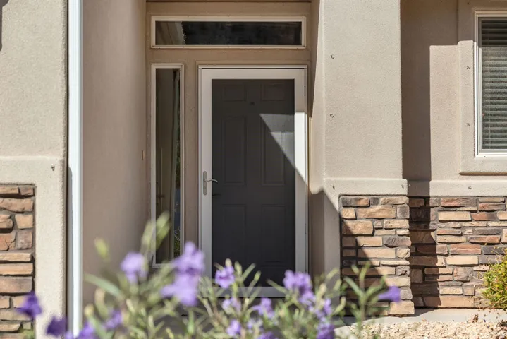 Stucco exterior with stone veneer accents, transom window, and sidelight
