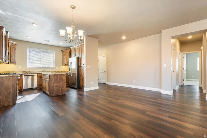 Spacious open-concept area featuring wood-finish flooring, a kitchen island, recessed lighting, and a chandelier
