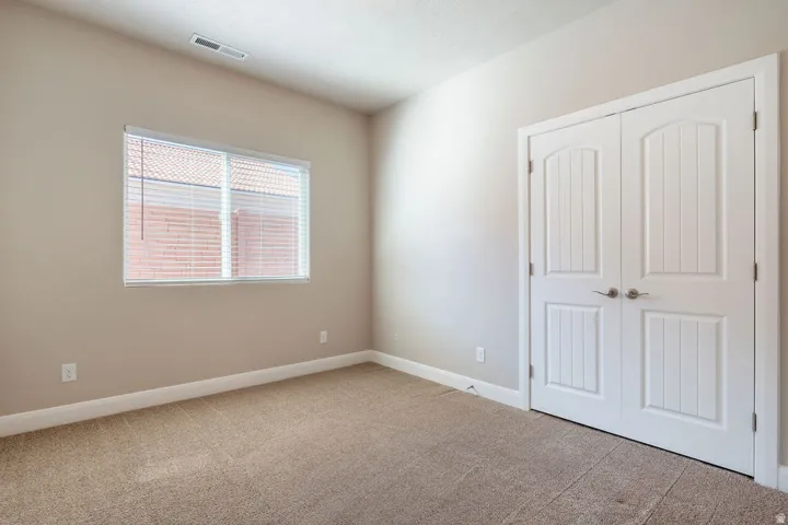 Neutral tone painted walls with a textured carpet, featuring white trim and baseboards