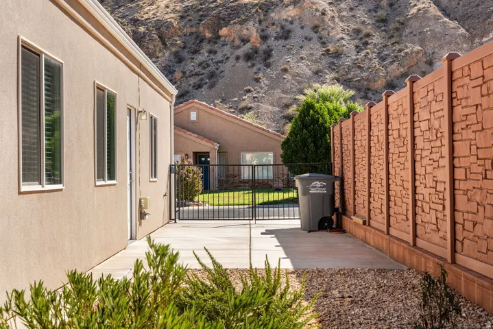 Stucco exterior with multiple windows, concrete patio, and decorative privacy fencing